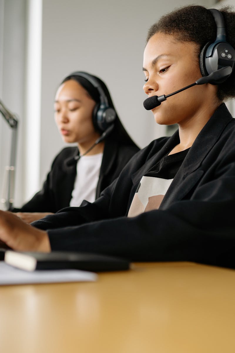 Two call center agents working at desks in an office setting with headsets.